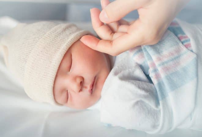 Baby sleeping with hand touching cheek